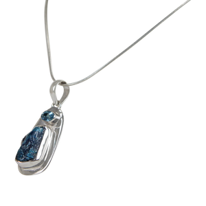 A beautiful rough Neon Apatite pendant accent with a Blue Topaz and elegantly hand set in Sterling Silver bazel.